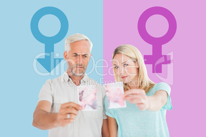 Composite image of unhappy couple holding two halves of torn pho