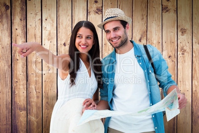 Composite image of happy hipster couple looking at map