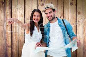 Composite image of happy hipster couple looking at map