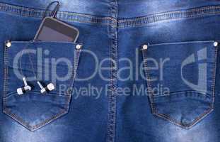 MP3 player and earphones sticking out of jeans pocket