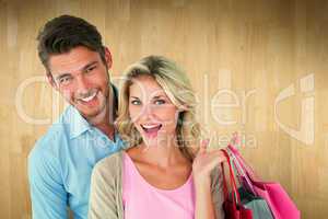 Composite image of attractive young couple holding shopping bags