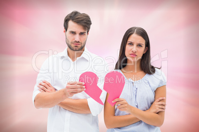 Composite image of upset couple holding two halves of broken hea