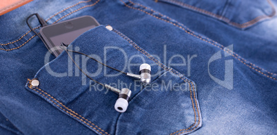 MP3 player and earphones sticking out of jeans pocket