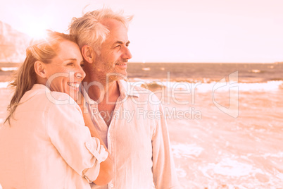 Happy couple hugging on the beach looking out to sea