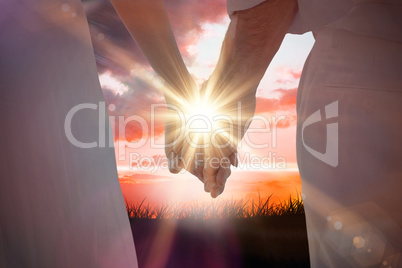 Composite image of bride and groom holding hands close up