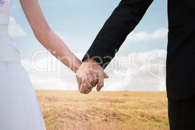 Composite image of mid section of newlywed couple holding hands