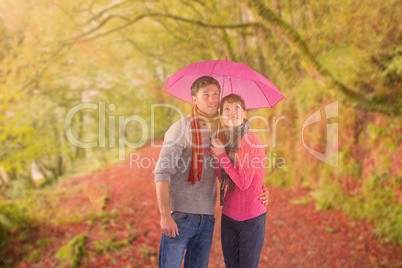 Composite image of couple standing underneath an umbrella