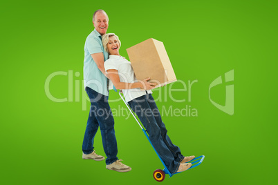 Composite image of fun older couple holding moving boxes