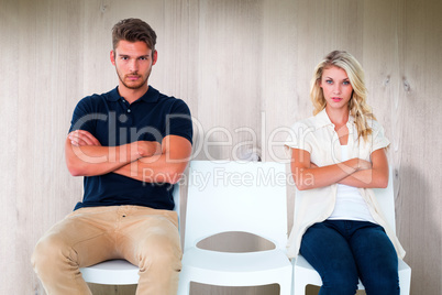 Composite image of young couple sitting in chairs not talking du