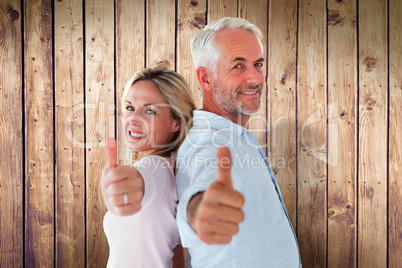 Composite image of smiling couple showing thumbs up together