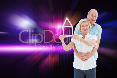 Composite image of happy older couple holding house shape