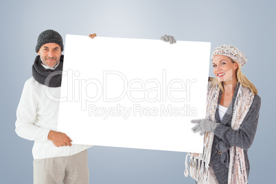 Composite image of smiling couple in winter fashion holding post