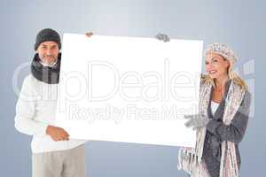 Composite image of smiling couple in winter fashion holding post