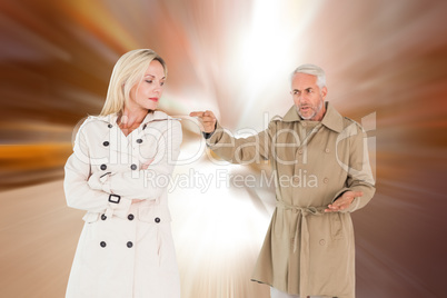 Composite image of angry couple fighting in trench coats