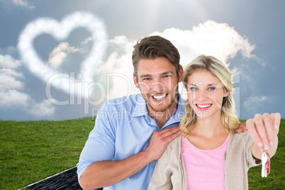 Composite image of attractive young couple showing new house key