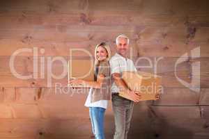 Composite image of happy couple holding moving boxes