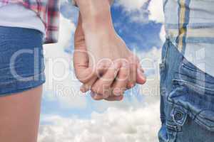 Composite image of couple in check shirts and denim holding hand