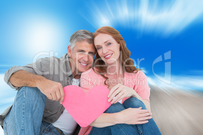 Composite image of casual couple holding pink heart