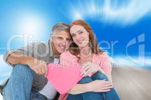 Composite image of casual couple holding pink heart