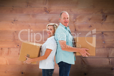Composite image of happy older couple holding moving boxes