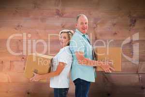 Composite image of happy older couple holding moving boxes