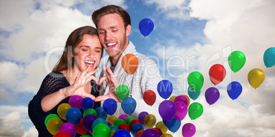 Composite image of happy couple forming heart with hands