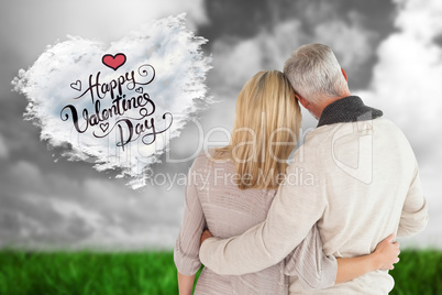 Composite image of happy couple standing with arms around