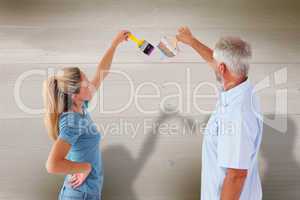 Composite image of happy couple painting wall with paintbrushes