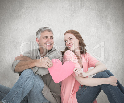 Composite image of casual couple holding pink heart