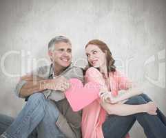 Composite image of casual couple holding pink heart