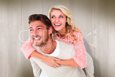 Composite image of handsome man giving piggy back to his girlfri