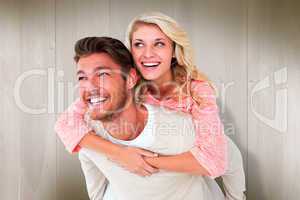 Composite image of handsome man giving piggy back to his girlfri