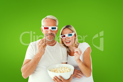 Composite image of happy couple wearing 3d glasses eating popcor