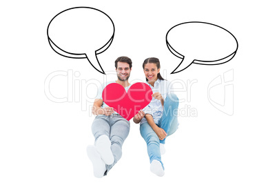 Composite image of cute couple sitting holding red heart