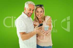 Composite image of happy couple looking at their smartphones