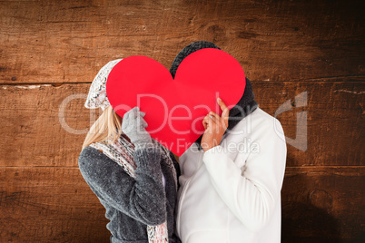 Composite image of couple in winter fashion posing with heart sh