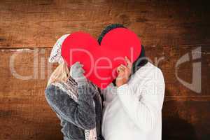 Composite image of couple in winter fashion posing with heart sh