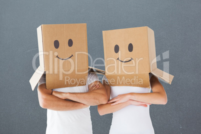 Composite image of couple wearing smiley face boxes on their hea