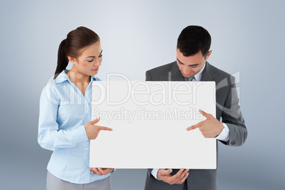 Composite image of business partners pointing at sign they are p