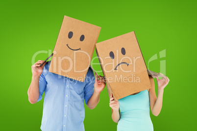 Composite image of couple wearing sad face boxes on their heads