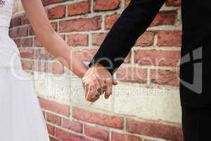 Composite image of mid section of newlywed couple holding hands