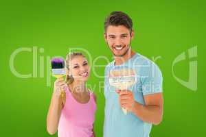 Composite image of young couple smiling and holding paintbrushes