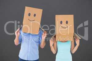 Composite image of couple wearing emoticon face boxes on their h