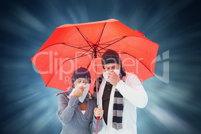 Composite image of mature couple blowing their noses under umbre