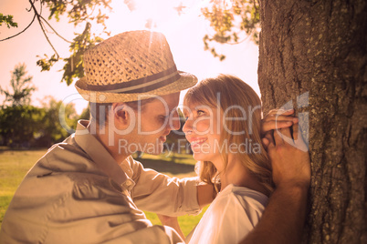 Cute smiling couple leaning against tree in the park