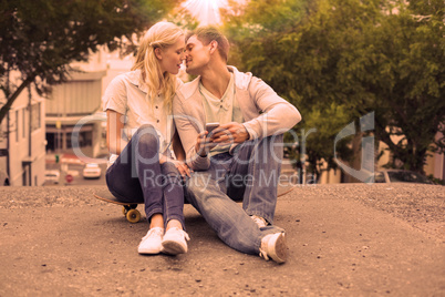 Hip young couple sitting on skateboard kissing