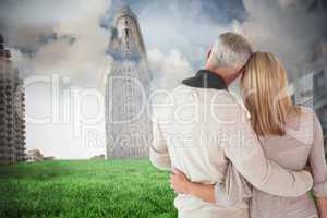 Composite image of happy couple standing with arms around