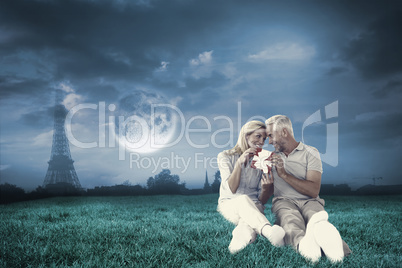 Composite image of happy couple sitting and holding present