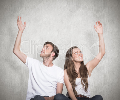 Composite image of happy young couple with hands raised