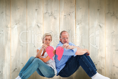 Composite image of sad mature couple holding a broken heart